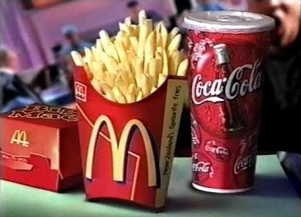 McDonald's fries in a red container with a Coca-Cola can on a table.
