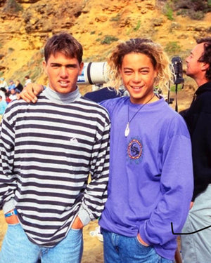 Two young men standing outdoors with a scenic background, wearing vintage Quiksilver clothing