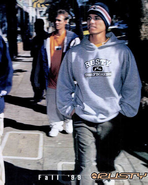 Person wearing a 'Rusty Surfboarding' hoodie on a street.