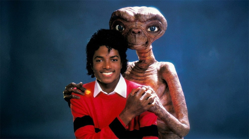 Person in a red sweater with a small alien character on a blue background
