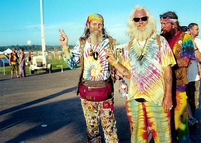 Three people in tie-dye and hippie-style clothing on a road.