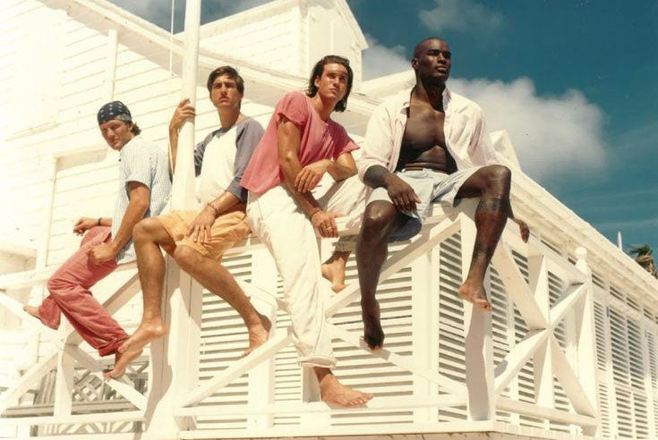 Four men sitting on a white architectural structure with a clear sky in the background