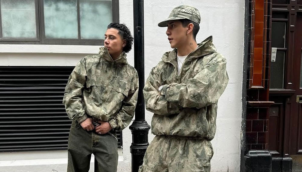 Two individuals wearing vintage Realtree camouflage outfits standing against a building.