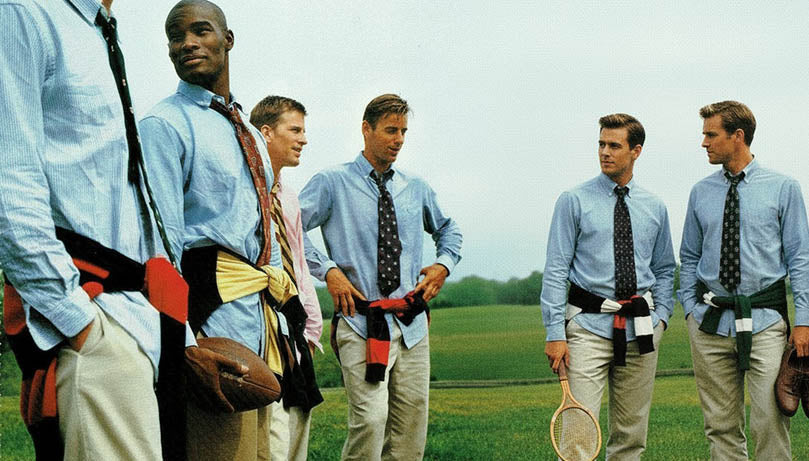 Men in light blue vintage Polo Ralph Lauren button up shirts and ties standing on a grassy field.